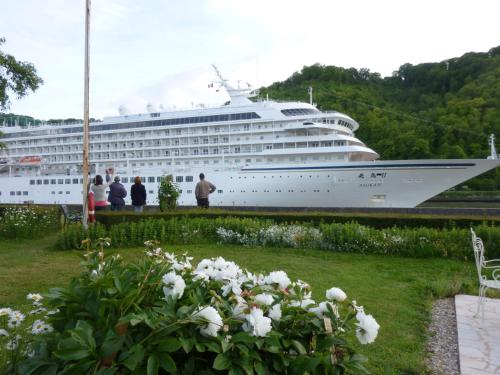 a cruise ship is docked in a harbor at Chambre d'hôtes Au Fil De L'eau in Jumièges
