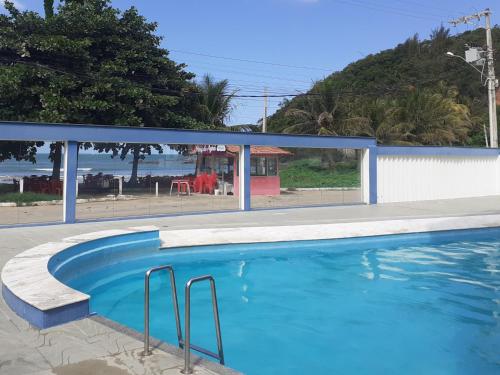 a blue swimming pool with a view of the ocean at Cobertura de Frente Para o Mar e Piscina Village das Ondas in Piúma