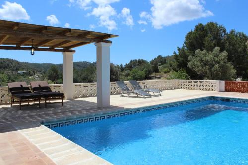 una piscina con pergolato e sedie accanto a un piscina di Villa Can Portmany a San Jose de sa Talaia