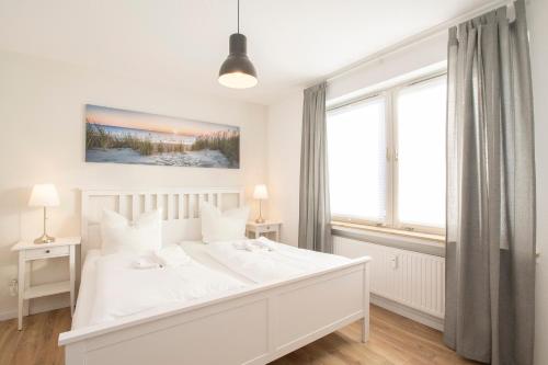 a white bedroom with a large white bed and windows at 'Dörpnüst' in Langeoog