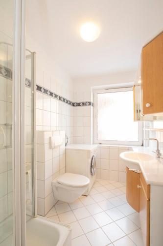 La salle de bains blanche est pourvue de toilettes et d'un lavabo. dans l'établissement 'Dörpnüst', à Langeoog