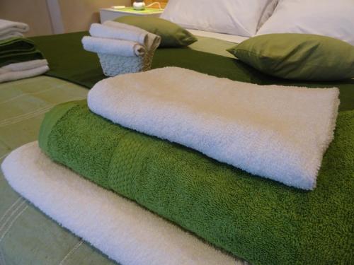 - une couverture verte et blanche sur un lit avec des serviettes dans l'établissement Suite Emilia, à SantʼIlario dʼEnza