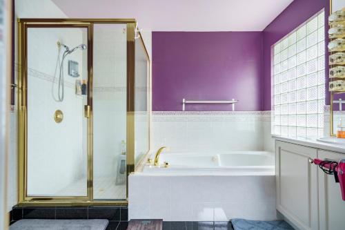 a bathroom with a tub and a shower with purple walls at Fraser River Richmond Bed and Breakfast in Richmond