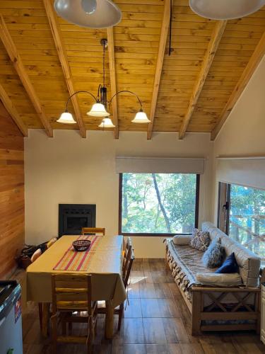 une salle à manger avec une table et un canapé dans l'établissement EL SUSURR0, à Villa Pehuenia