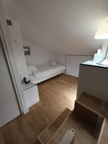 Cette petite chambre blanche dispose d'un lit et de parquet. dans l'établissement Chez Mamarina - Quadruplex - Marina Deauville, à Deauville