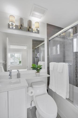 a white bathroom with a toilet and a shower at Family-Friendly, 3 Bed House - Private Backyard-Central Location in Vancouver