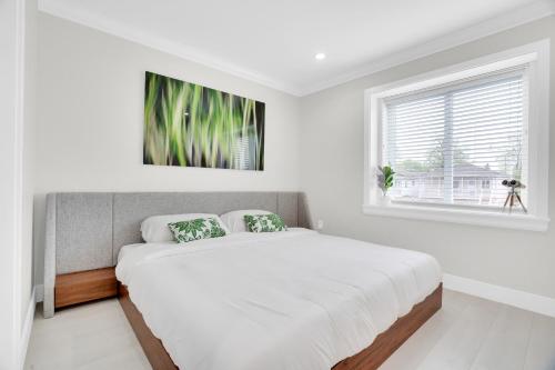 a white bedroom with a large bed and a window at Family-Friendly, 3 Bed House - Private Backyard-Central Location in Vancouver