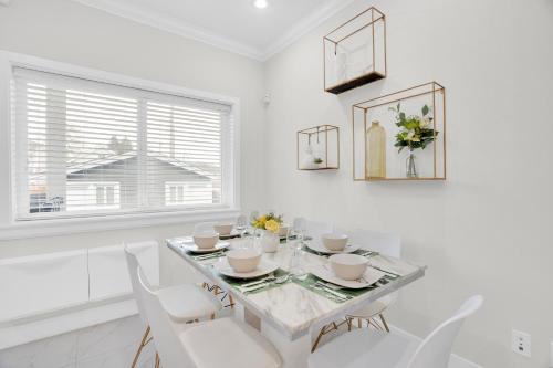 a white dining room with a table and white chairs at Family-Friendly, 3 Bed House - Private Backyard-Central Location in Vancouver