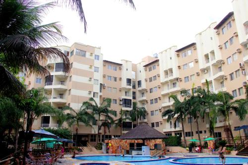 a large apartment building with a swimming pool and palm trees at Thermas Paradise in Rio Quente