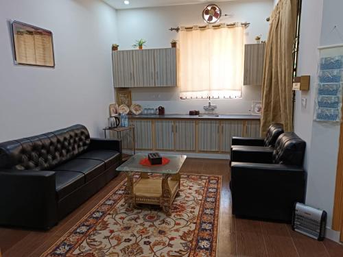 a living room with two leather couches and a table at Islamabad Comfort Home in Islamabad
