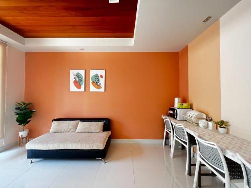 a bedroom with orange walls and a bed and a table at Smile Residence at Kaset-Sena in Ban Yang