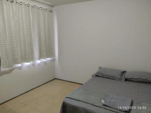 ein weißes Schlafzimmer mit einem Bett und einem Fenster in der Unterkunft Andres home casa J in Governador Valadares