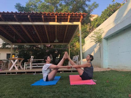 Dos mujeres haciendo una pose de yoga en la hierba en Lemon Art Hotel Apartments, en Tolo