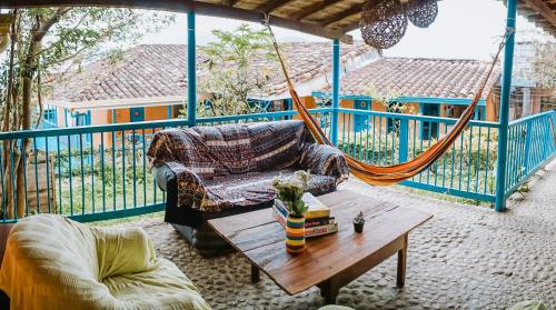 eine Veranda mit einer Hängematte, einem Sofa und einem Tisch in der Unterkunft Parcerito's Hostel in Jericó