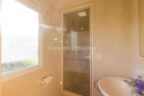 La salle de bains est pourvue d'une douche, d'un lavabo et d'une fenêtre. dans l'établissement Great 6 Berth Caravan For Hire At Sunnydale Holiday Park In Skegness Ref 35150tm, à Louth