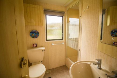 baño con aseo y lavabo y ventana en Superb Caravan With Decking Close To Hunstanton Beach In Norfolk Ref 23060s, en Hunstanton