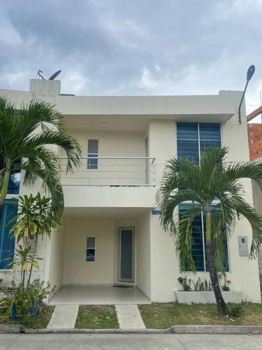 a white house with two palm trees in front of it at Casa Acacías - Meta in Acacías
