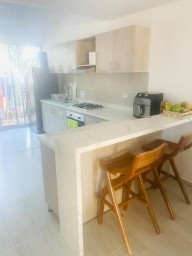 a kitchen with a counter and two wooden chairs at Casa Acacías - Meta in Acacías