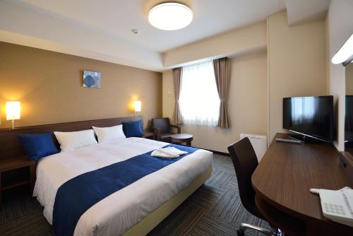 a hotel room with a bed and a desk and a television at Sunrise Inn Iwaki in Iwaki