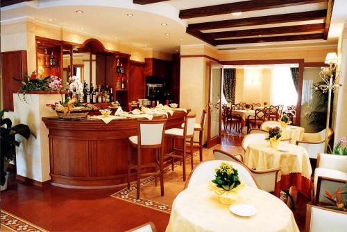 un restaurante con un bar con mesas y sillas blancas en Hotel Antico Masetto, en Lamporecchio