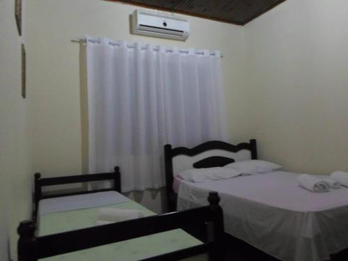 two twin beds in a room with a window at Pousada Laura / Ziza in Foz do Iguaçu