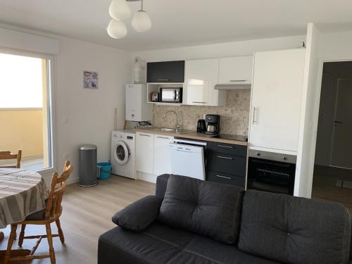 un salon avec un canapé et une cuisine dans l'établissement Appartement Neuf Centre-Ville Fort-Mahon-Plage avec Balcon et Parking, Idéal Famille - FR-1-482-114, à Fort-Mahon-Plage