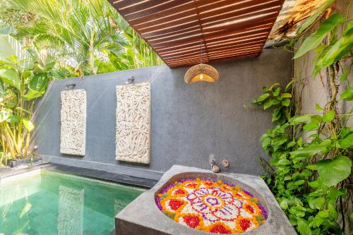 a pizza sitting on a table next to a swimming pool at Seminyak Sanctuary Villa by Ini Vie Hospitality in Legian