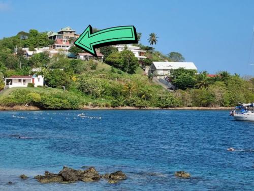 ein Boot in einem Wasserkörper mit einem grünen Pfeil in der Unterkunft Villa Nautilia , vue mer, proche plage in Les Trois-Îlets