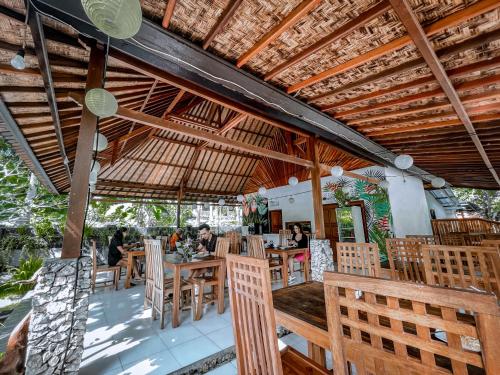 a restaurant with tables and chairs and a wooden ceiling at Mertha Sari Resto & Bungalow in Klungkung