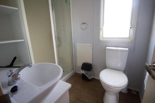 a white bathroom with a toilet and a sink at Caravan With Decking Within Walking Distance To Hunstanton Beach Ref 23054s in Hunstanton