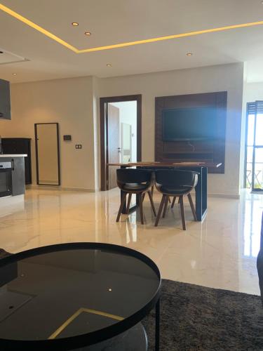 a living room with a table and chairs and a television at Belle appartement situé à la plage mahdia in Kenitra