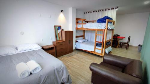 um quarto com uma cama, um sofá e beliches em Home Away em Sucre