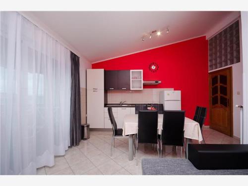 eine Küche mit roten Wänden sowie einem Tisch und Stühlen in der Unterkunft Apartmani 'Mirijana Gabrić' A3 in Lopar