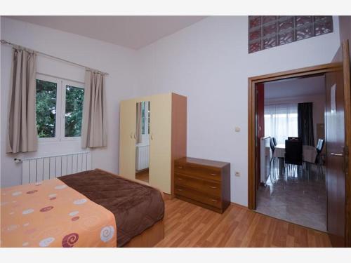 a bedroom with a bed and a dresser and a dining room at Apartmani 'Mirijana Gabrić' A3 in Lopar
