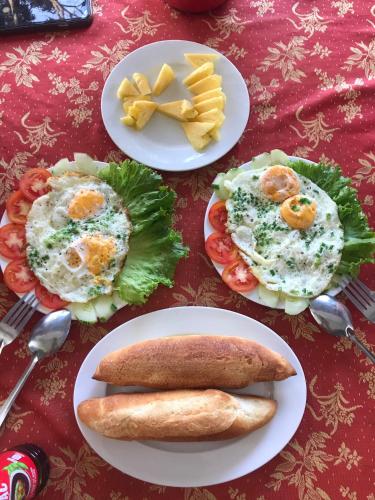 a table topped with plates of food with eggs and bread at Homestay Vân Đức Cù Lao Chàm in Tân Hiệp