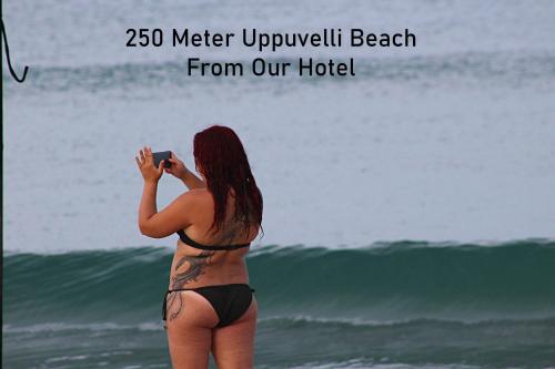 a woman in a bikini taking a picture of the ocean at Rea Beach Way Hotel in Trincomalee