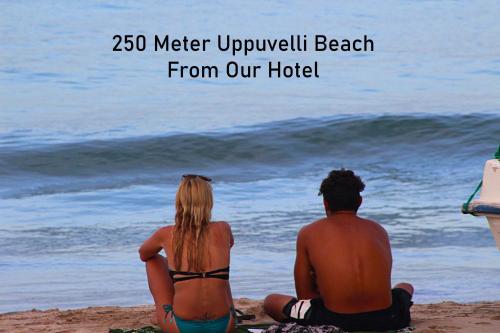 a couple sitting on the beach looking at the ocean at Rea Beach Way Hotel in Trincomalee