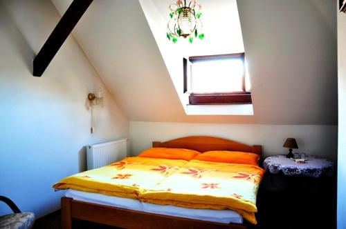 1 dormitorio con 1 cama con almohadas de color naranja y ventana en Penzion Podhradí, en Český Krumlov