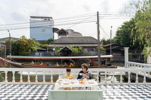 two children sitting at a table in front of a boat at Arpo Pool Villa Riverside Bangkok in Bangkok