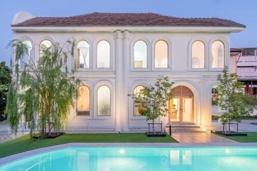 a large white house with a swimming pool in front of it at Arpo Pool Villa Riverside Bangkok in Bangkok