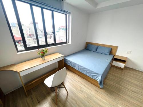 1 dormitorio con cama, escritorio y ventana en Nhà Như Ngọc/NN serviced apartment, en Hanói