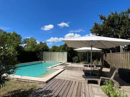 einen Pool mit einem Sonnenschirm und Stühlen sowie einem Tisch mit einem Sonnenschirm in der Unterkunft Mas de l'Estiou in Monteux