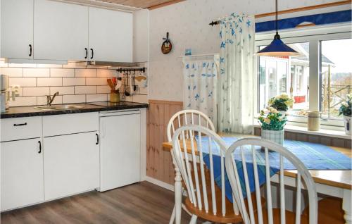 cocina con armarios blancos, mesa y sillas en Beautiful Home In Ronneby With House Sea View, en Ronneby