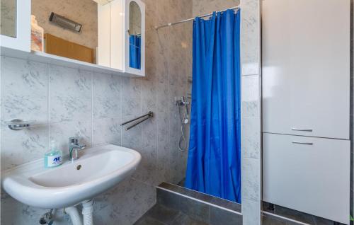 a bathroom with a sink and a blue shower curtain at Nice Home In Barbariga With 3 Bedrooms, Wifi And Jacuzzi in Barbariga