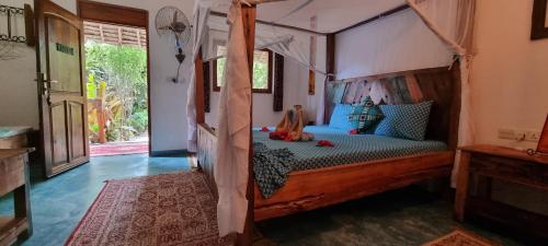 a bedroom with a wooden bed with a canopy at Salama & Mbuyuni Bungalows in Matemwe