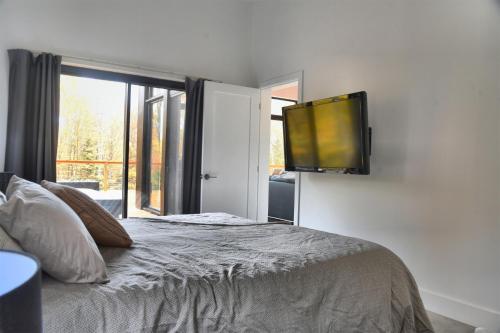 a bedroom with a bed with a flat screen tv on the wall at KALLM-Mont-Tremblant chalet with hot tub, pond & beach on private 7acre estate in Lac-Superieur