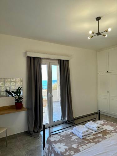 a bedroom with a bed and a large window at Nautica Hotel Apartments in Stavromenos