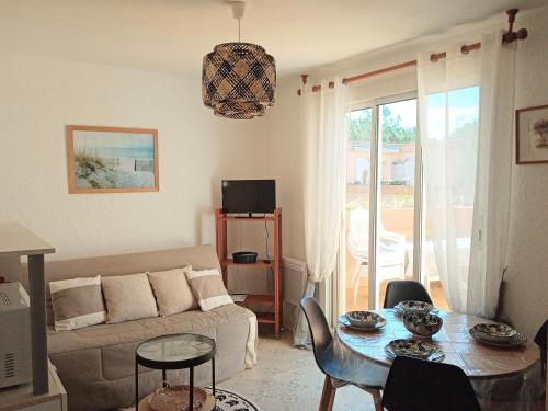 a living room with a couch and a table with chairs at Les Boramars 4 23 climatisé wifi 300m plage in Argelès-sur-Mer