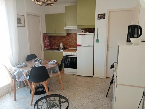 a kitchen with a table and a white refrigerator at Les Boramars 4 23 climatisé wifi 300m plage in Argelès-sur-Mer