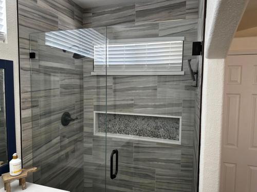 een douche met een glazen deur in de badkamer bij Valley Magnolia. Tranquil + Stylish. Near Hospital in Hanford